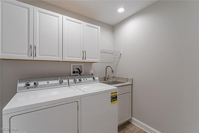 laundry area featuring washer and dryer, cabinets, light wood-type flooring, and sink