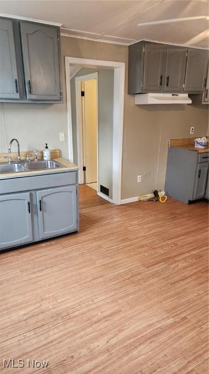 kitchen with gray cabinets, sink, light wood-type flooring, and ornamental molding