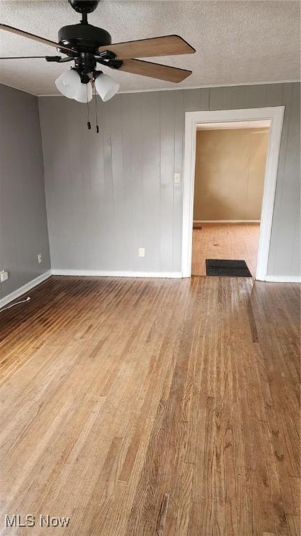 empty room with ceiling fan, hardwood / wood-style floors, and a textured ceiling