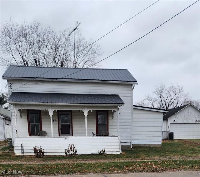 bungalow-style house with covered porch, a garage, a front lawn, and an outdoor structure