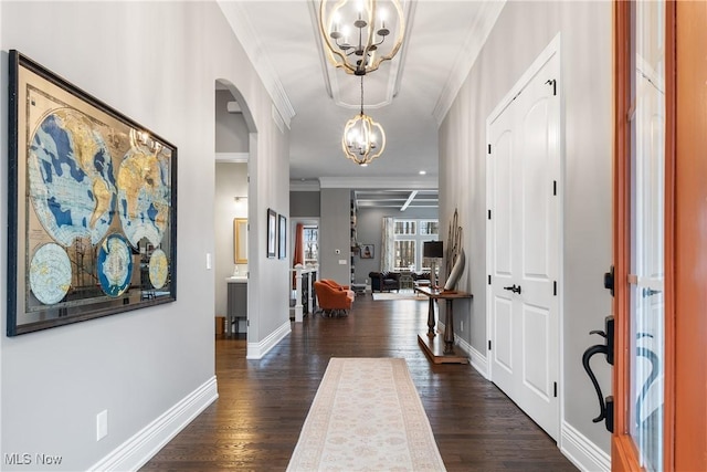 entrance foyer featuring dark hardwood / wood-style floors, ornamental molding, and an inviting chandelier