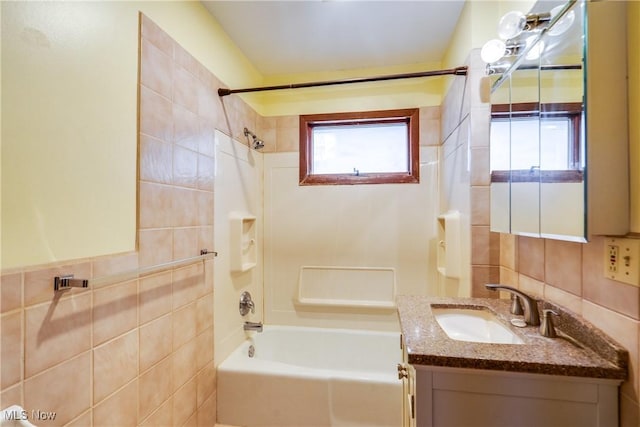 bathroom with tiled shower / bath, vanity, and tile walls