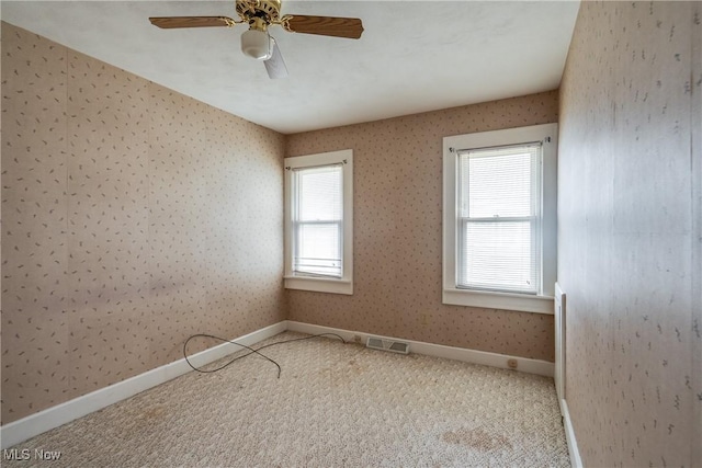 carpeted spare room featuring ceiling fan