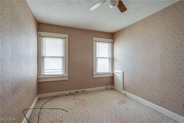 carpeted spare room featuring a wealth of natural light and ceiling fan