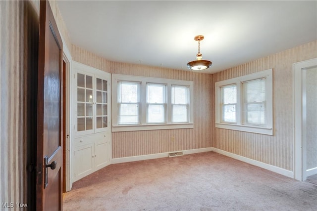 unfurnished room with light colored carpet and a wealth of natural light