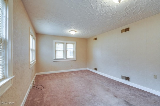 carpeted empty room featuring a textured ceiling