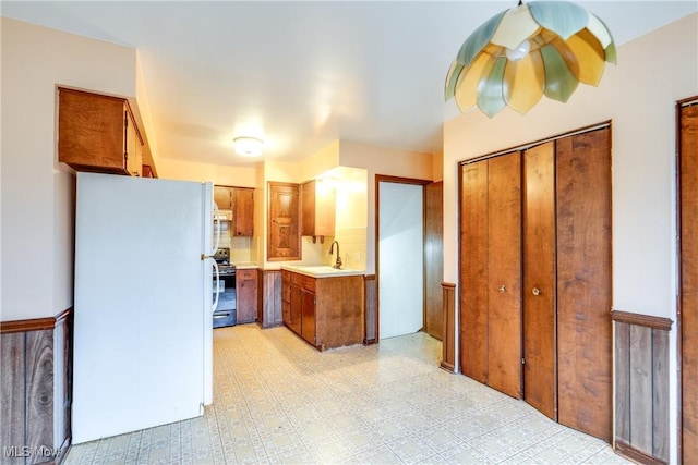 kitchen with black stove, white fridge, and sink