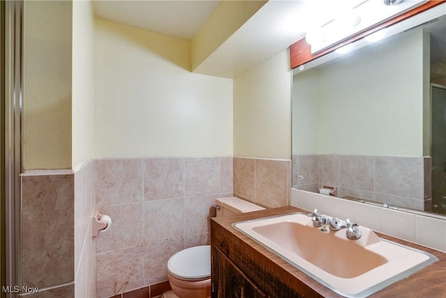 bathroom with vanity, tile walls, and toilet