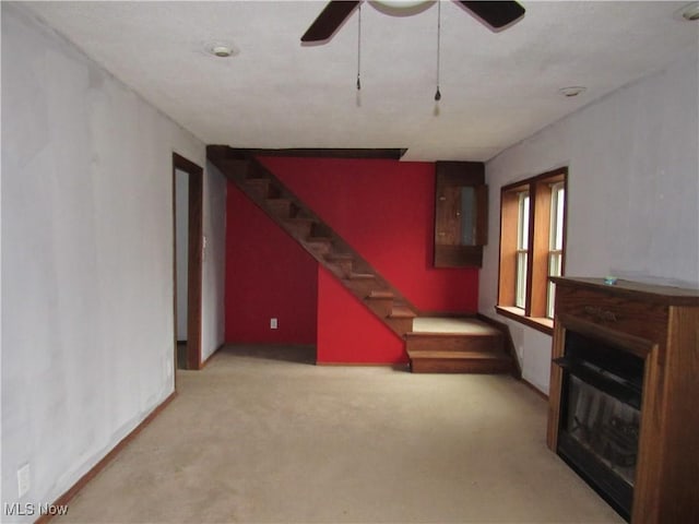 unfurnished living room featuring light colored carpet and ceiling fan