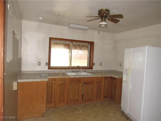 kitchen with ceiling fan, white fridge with ice dispenser, and sink