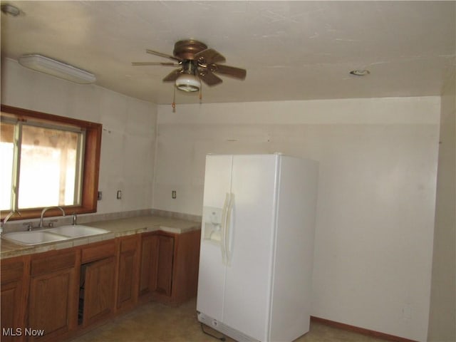 kitchen featuring ceiling fan, white fridge with ice dispenser, and sink