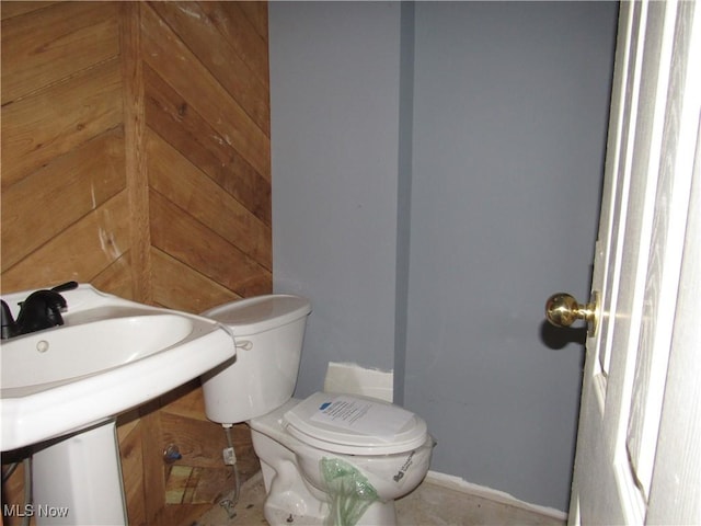 bathroom featuring wood walls and toilet