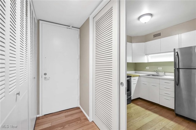 kitchen featuring white cabinets, light wood-type flooring, and appliances with stainless steel finishes