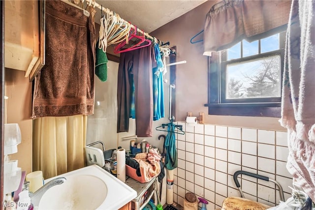 bathroom featuring walk in shower, tile walls, and sink