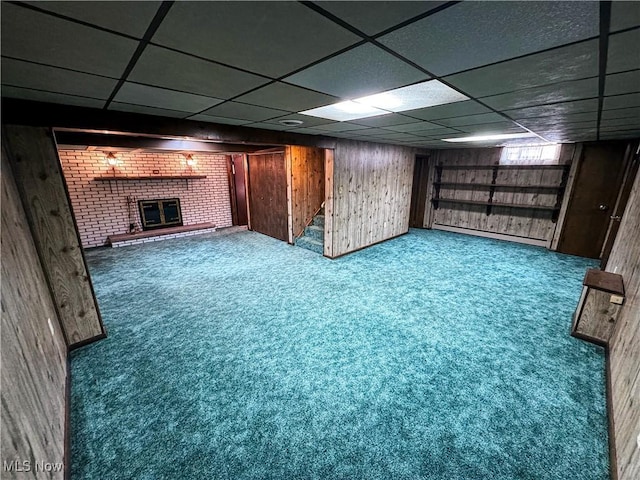 basement featuring a drop ceiling, carpet, and a brick fireplace