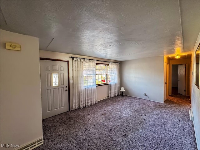 carpeted foyer entrance with a textured ceiling