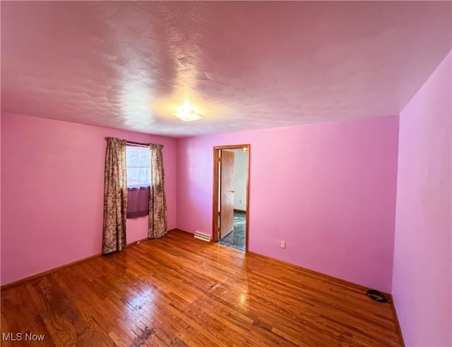 spare room with a baseboard radiator and light hardwood / wood-style flooring