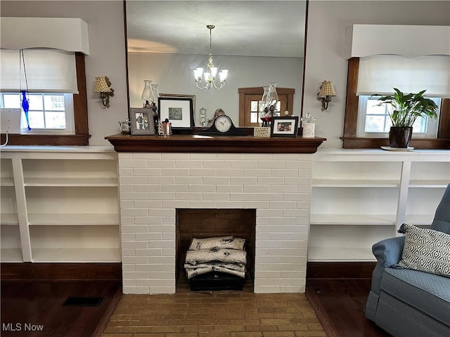 details with hardwood / wood-style floors, a brick fireplace, and a notable chandelier