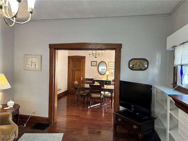 living room featuring ornamental molding, an inviting chandelier, and dark wood-type flooring