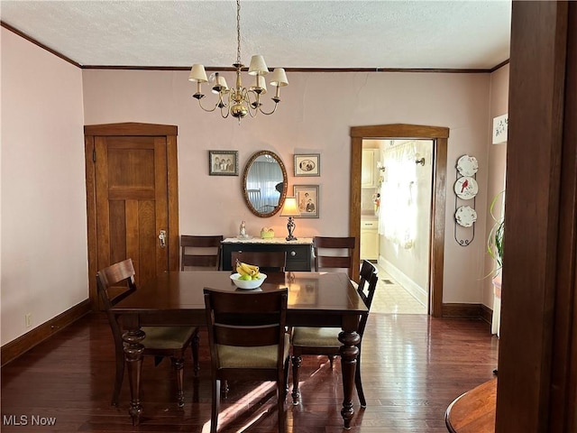 dining space with a textured ceiling, a chandelier, dark hardwood / wood-style floors, and ornamental molding