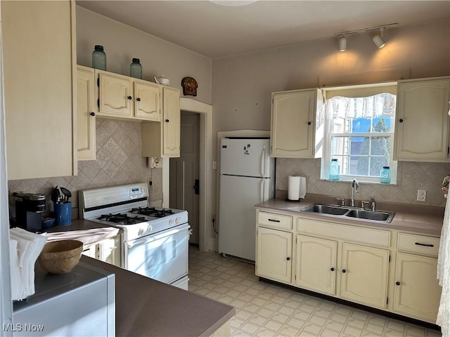 kitchen featuring decorative backsplash, sink, rail lighting, and white appliances