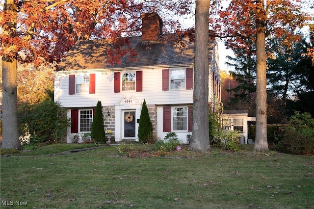 view of front facade with a chimney and a front yard