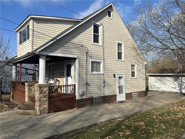 back of house featuring covered porch, an outdoor structure, and a garage