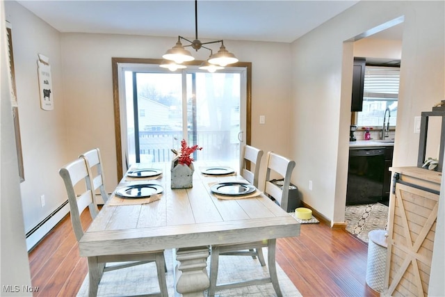 dining space with plenty of natural light, wood-type flooring, a baseboard heating unit, and an inviting chandelier