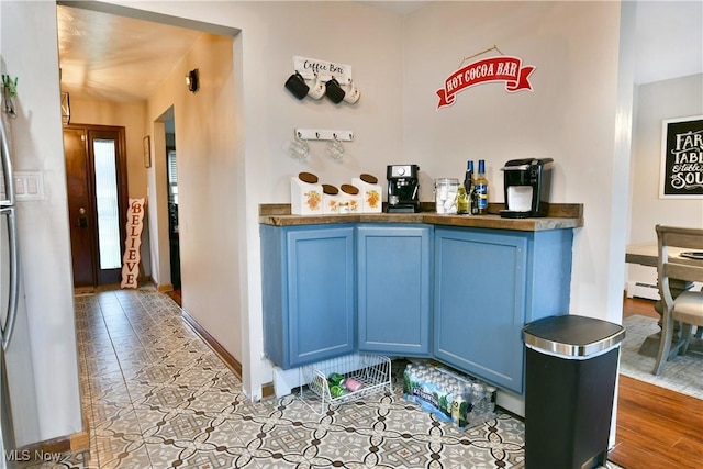 bar featuring blue cabinetry, light tile patterned floors, and a baseboard heating unit