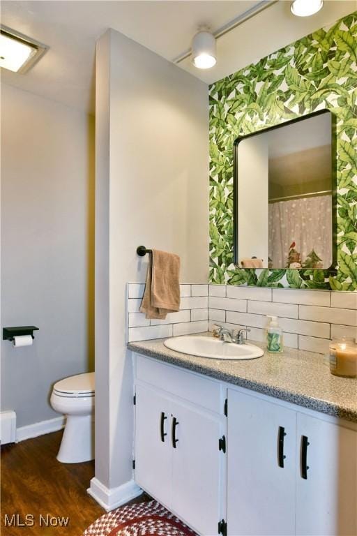 bathroom featuring hardwood / wood-style flooring, vanity, toilet, and backsplash