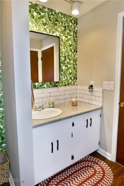 bathroom with backsplash, vanity, and hardwood / wood-style flooring