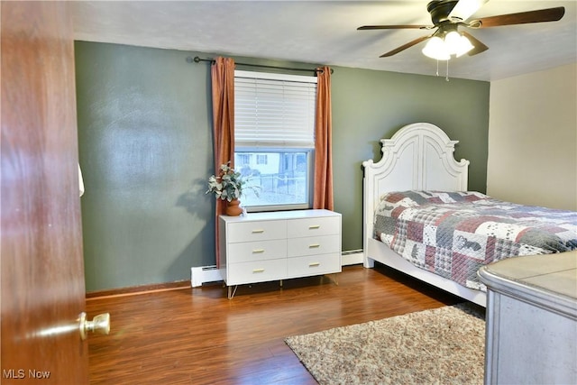 bedroom featuring dark wood-type flooring, ceiling fan, and a baseboard heating unit