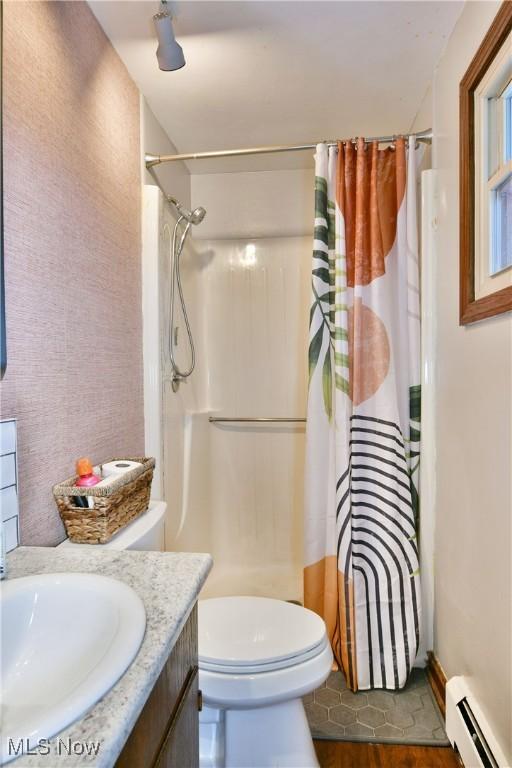 bathroom featuring a shower with shower curtain, vanity, baseboard heating, hardwood / wood-style floors, and toilet