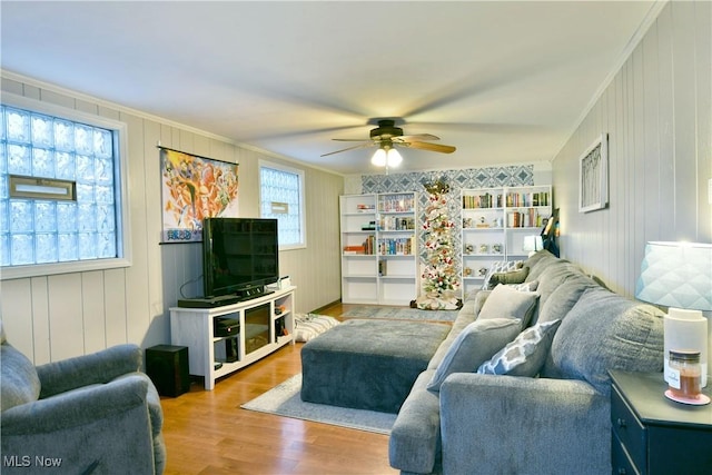 living room with wood-type flooring, ceiling fan, and ornamental molding