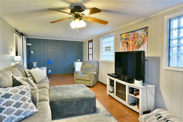 living room featuring hardwood / wood-style floors, wooden walls, ceiling fan, and ornamental molding