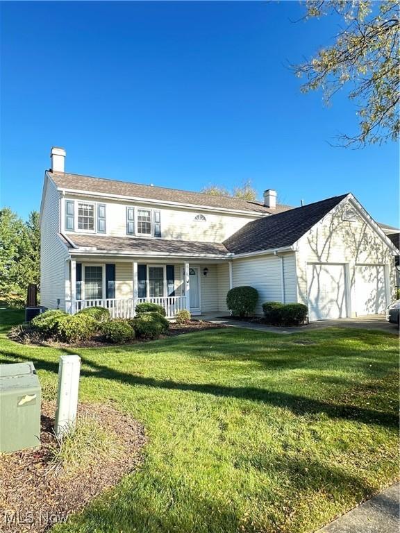 view of front of property featuring a garage, covered porch, and a front lawn