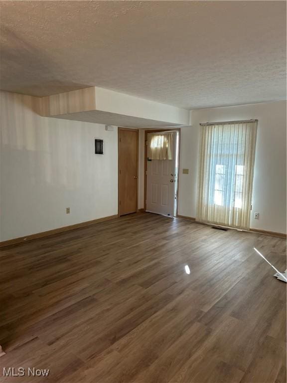 unfurnished living room with dark hardwood / wood-style flooring and a textured ceiling