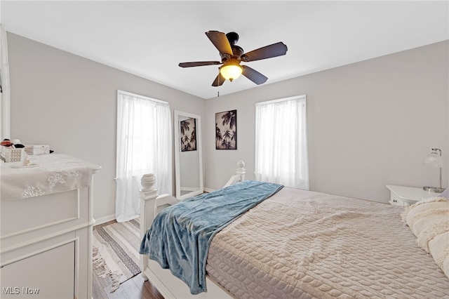 bedroom with multiple windows, ceiling fan, and light hardwood / wood-style floors