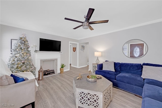 living room with ceiling fan, light wood-type flooring, and ornamental molding