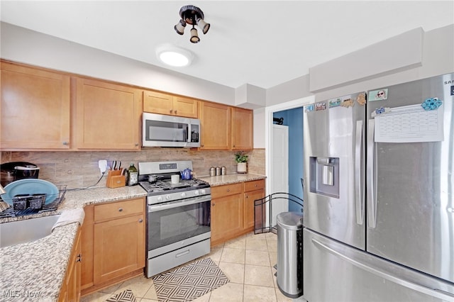 kitchen featuring light stone counters, sink, stainless steel appliances, and tasteful backsplash