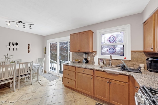 kitchen with tasteful backsplash, light stone counters, stainless steel range, sink, and light tile patterned floors