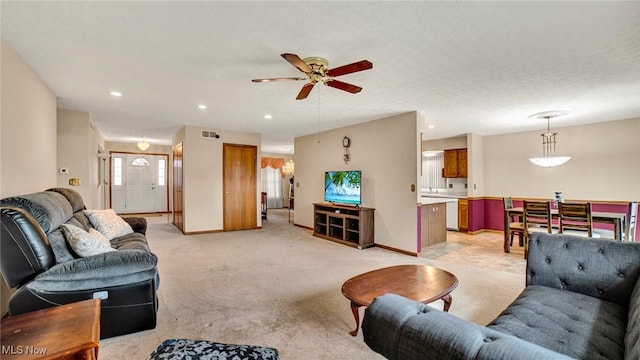 carpeted living room featuring ceiling fan and a textured ceiling