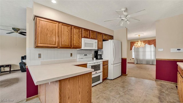 kitchen with white appliances, ceiling fan with notable chandelier, hanging light fixtures, decorative backsplash, and kitchen peninsula