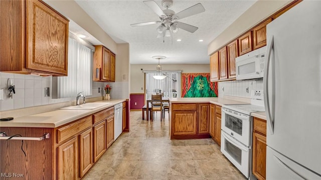 kitchen with sink, kitchen peninsula, pendant lighting, a textured ceiling, and white appliances