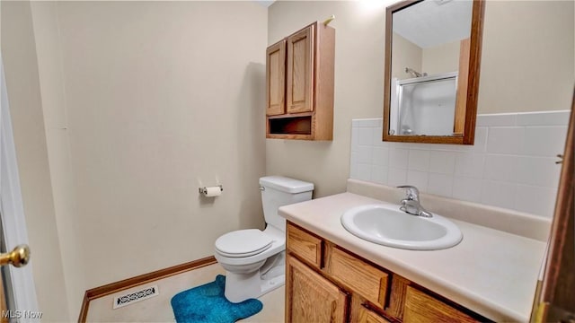 bathroom featuring vanity, toilet, a shower with shower door, and backsplash