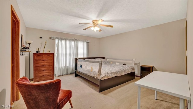 bedroom featuring a textured ceiling, light colored carpet, and ceiling fan