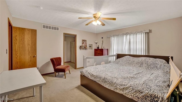 bedroom featuring ceiling fan, light carpet, and a textured ceiling