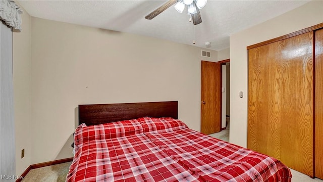 unfurnished bedroom featuring light carpet, a textured ceiling, a closet, and ceiling fan