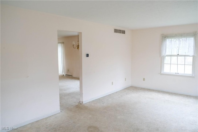 unfurnished room featuring a chandelier and light colored carpet