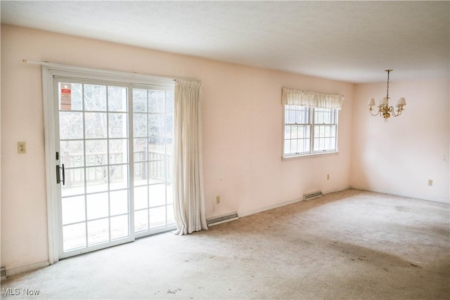 carpeted spare room featuring a chandelier and plenty of natural light